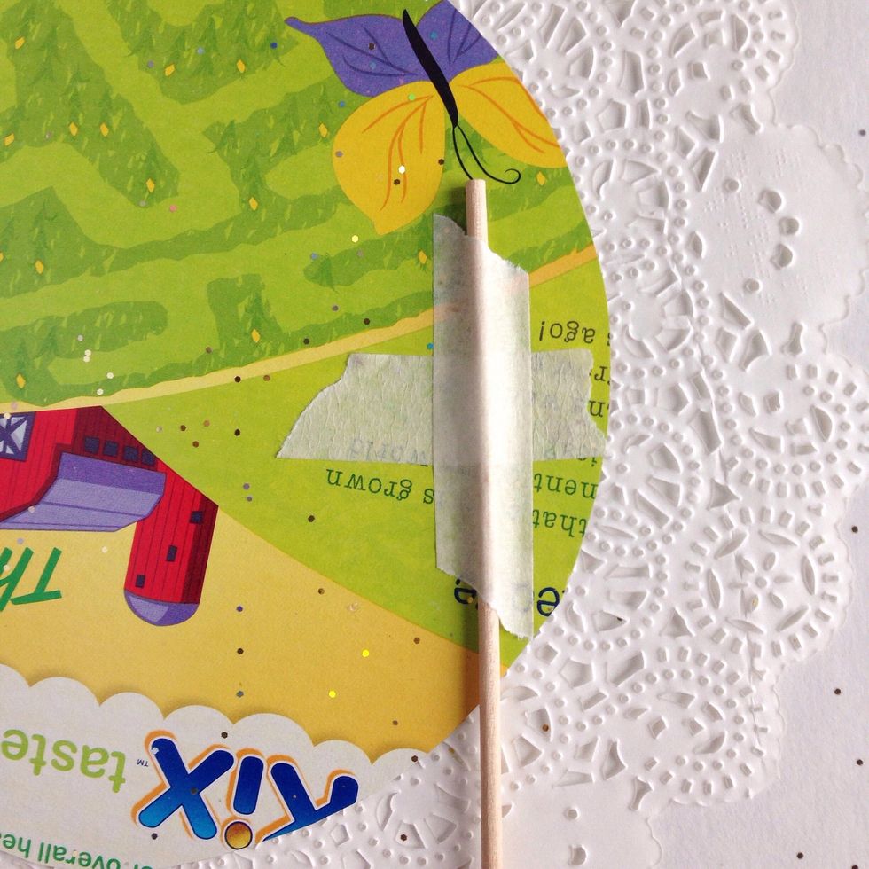 Attach a skewer to the doily with masking tape.