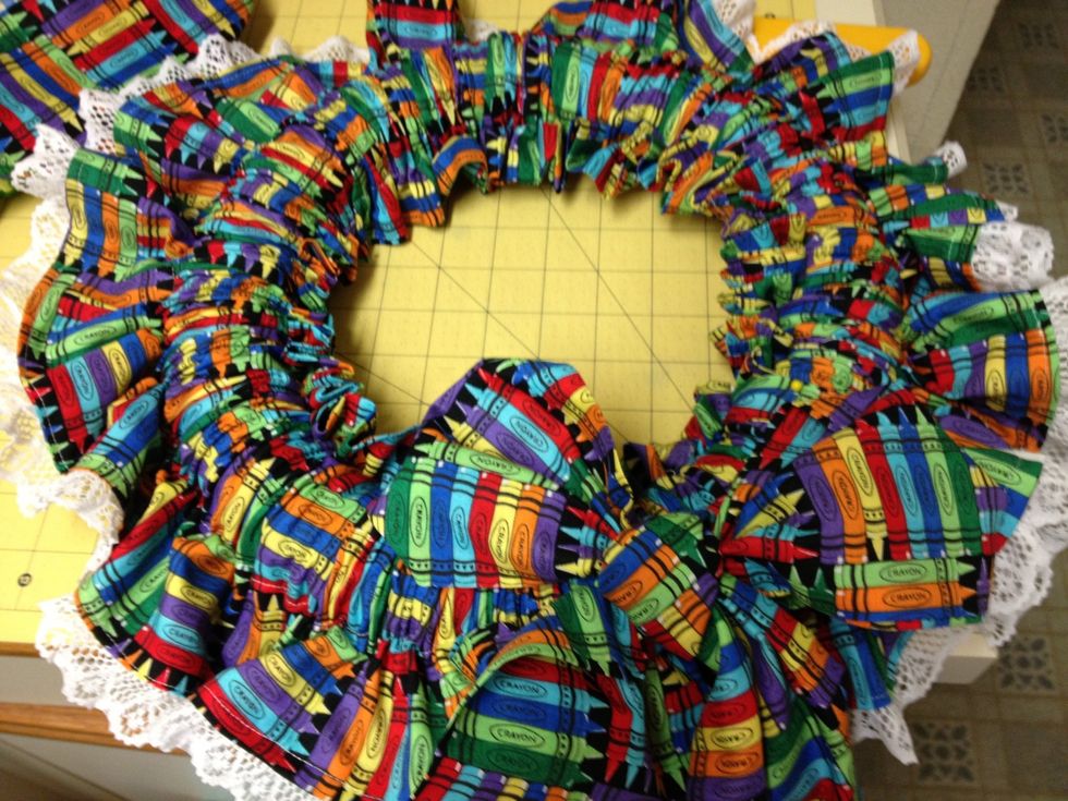 Attach it to the wreath.  You can tack it by hand stitching or use pins into the styrofoam. That's it