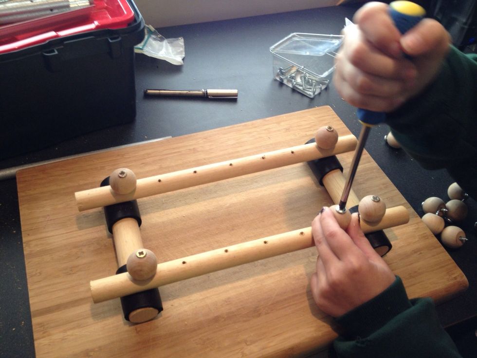Attach the remaining 10 knobs to the base of your xylophone. She used a screw driver to attach hers, you can also use a drill.