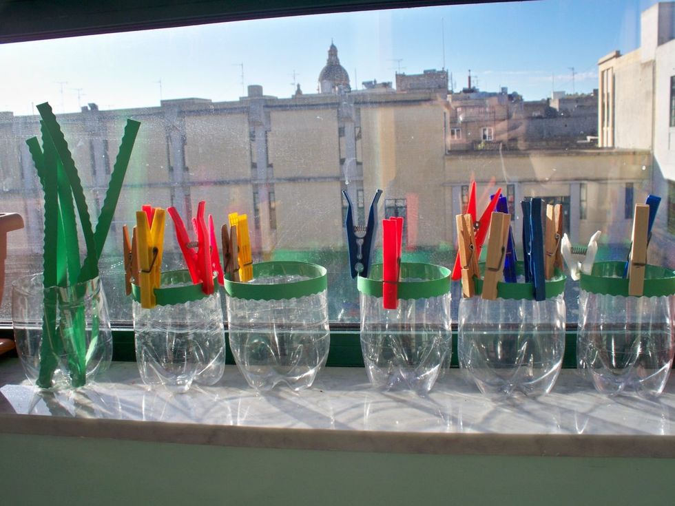 Attach the strip of green paper with some PVA glue to the edge of the bottle. Hold the edge using pegs.