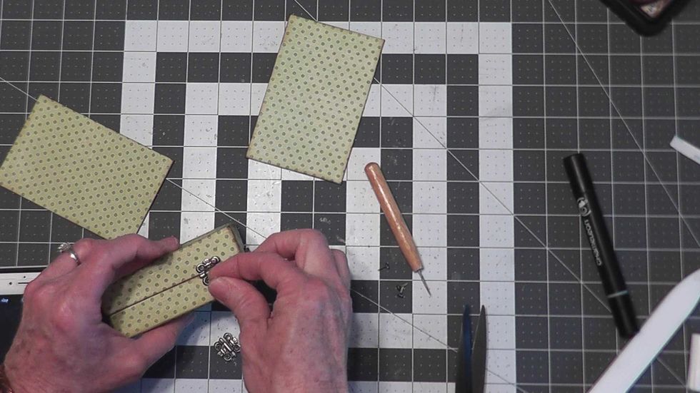 Attach the two hinges to your box with brads.  Open up the prongs on the inside and secure with a bit of Glossy Accent.  Make sure you do not glue your box shut.  Allow to dry.