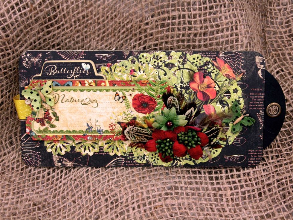 Back cover:  Add a diecut oval doily on the right.  Add a sticker from the sticker sheet to the left, add a border cut above & below the sticker, then embellish with chipboard, flowers & feathers.
