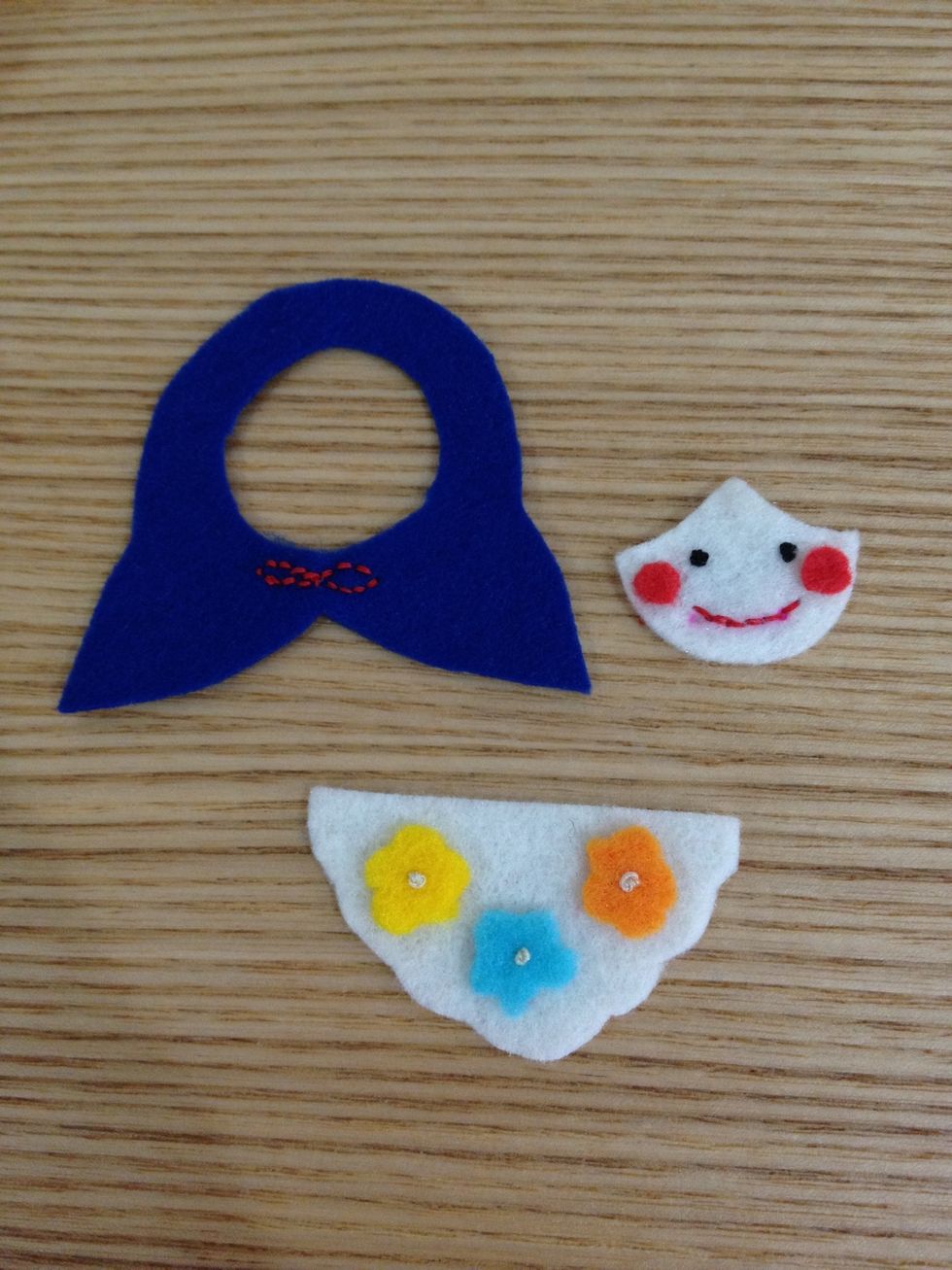 Backstitch for the doll mouth and the ribbon. Then attach the cheeks to the face. Make a knot for eyes, also the flower stigma! (Check the video on my cactus pin cushion guide for making the knot!) \ud83d\ude0a