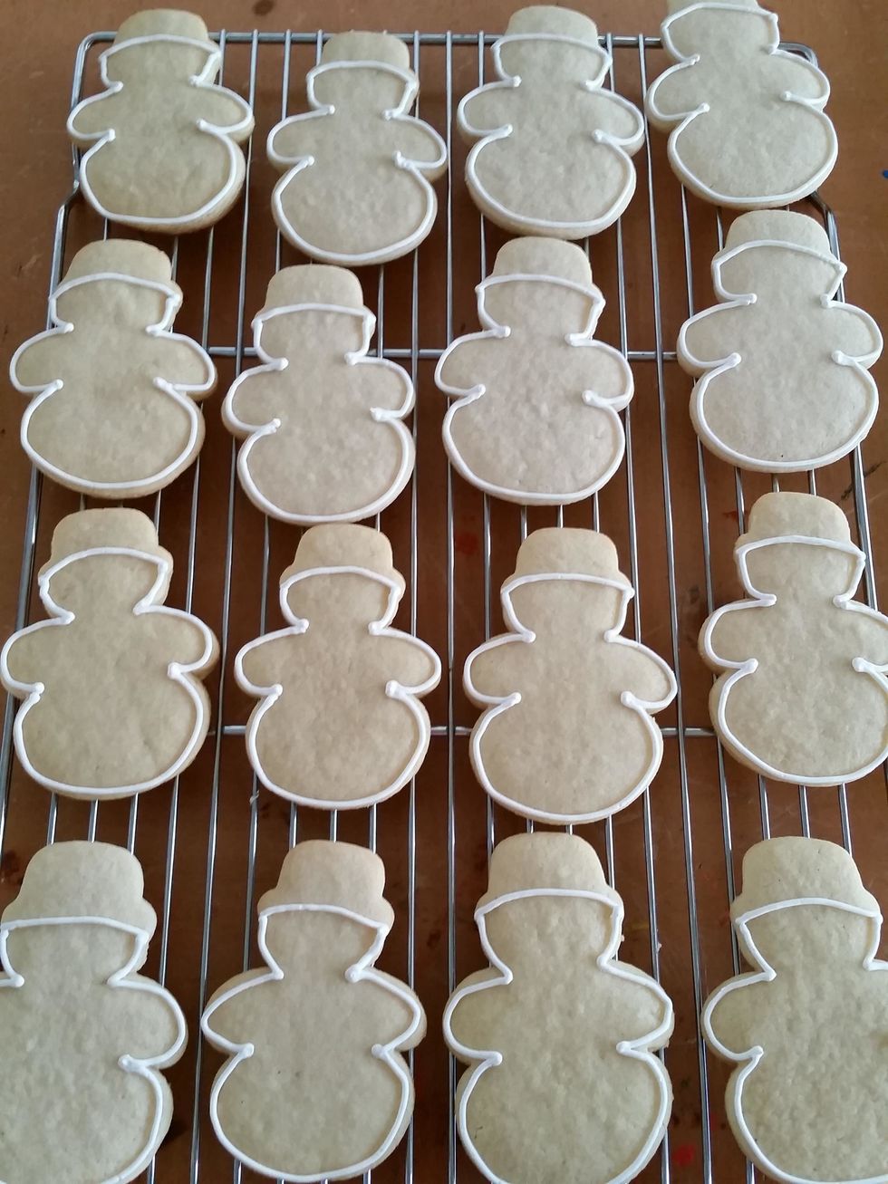 Bake snowmen on parchment paper 375 degrees for 8-10 minutes. Allow to cool. Take one solid snowman (this will be the top of the cookie) and outline with royal icing.