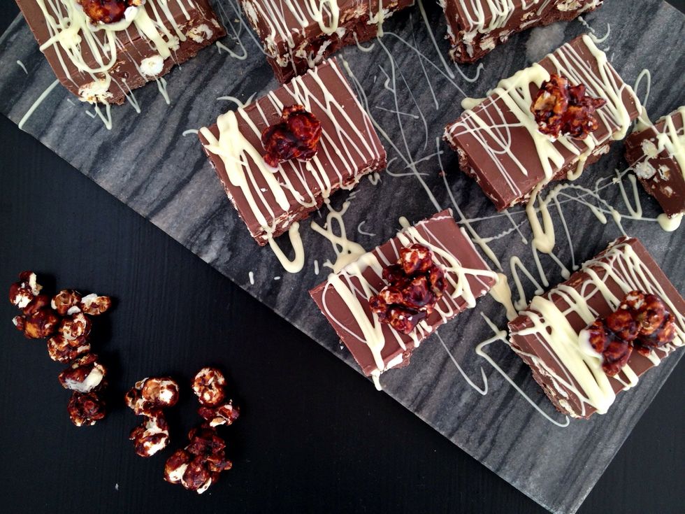 Before cutting, leave to cool completely overnight. To cut, bring chocolate to room temperature and use a heated knife if possible. Drizzle with white chocolate and decorate with popcorn pieces.