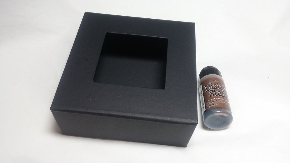 Begin by adding a layer of brown distress stain. This base layer will peek through when you spray it with water in later steps.