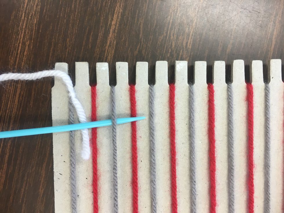 Begin by threading your needle under and over the base yarn. Wherever you begin, you will continue. If you start going under the gray, continue under each gray, and over each red all the way across.
