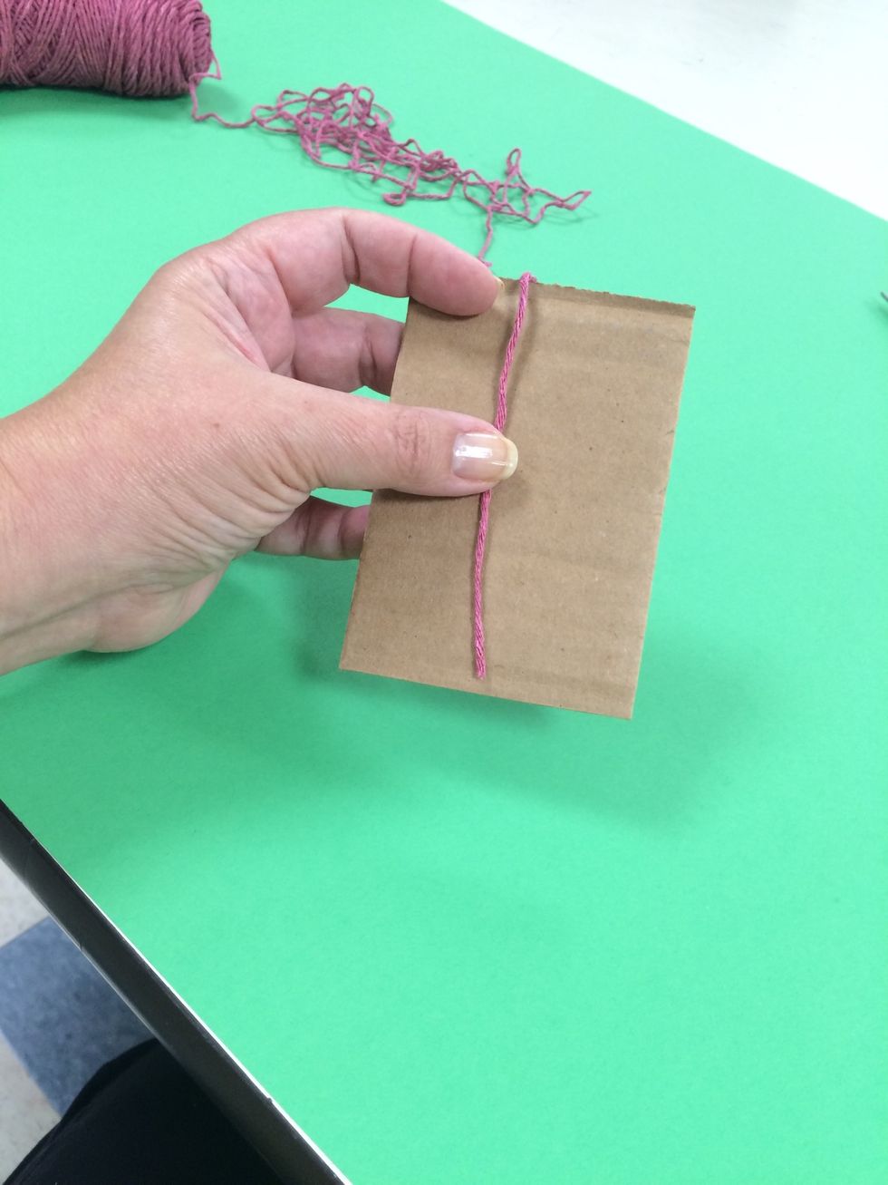 Begin by wrapping the yarn around the cardboard.