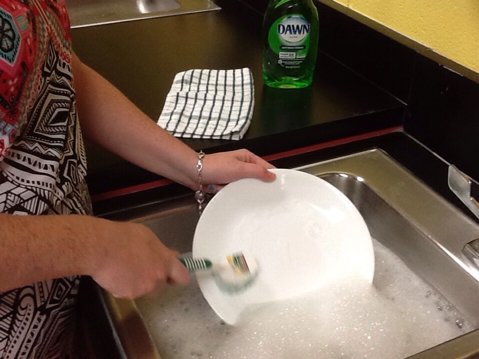 Begin cleaning scraped dishes using scrubber or wash cloth. Don't forget to scrub the back as well.