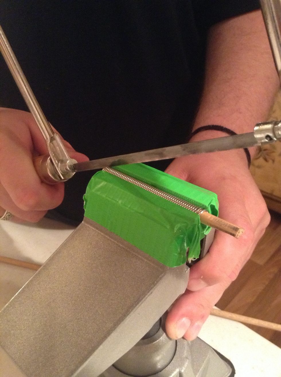 Begin cutting into the end of the wooden rod to create a guide into the first ring. Make sure to cut only one end of the coil and not to cut all the way through.