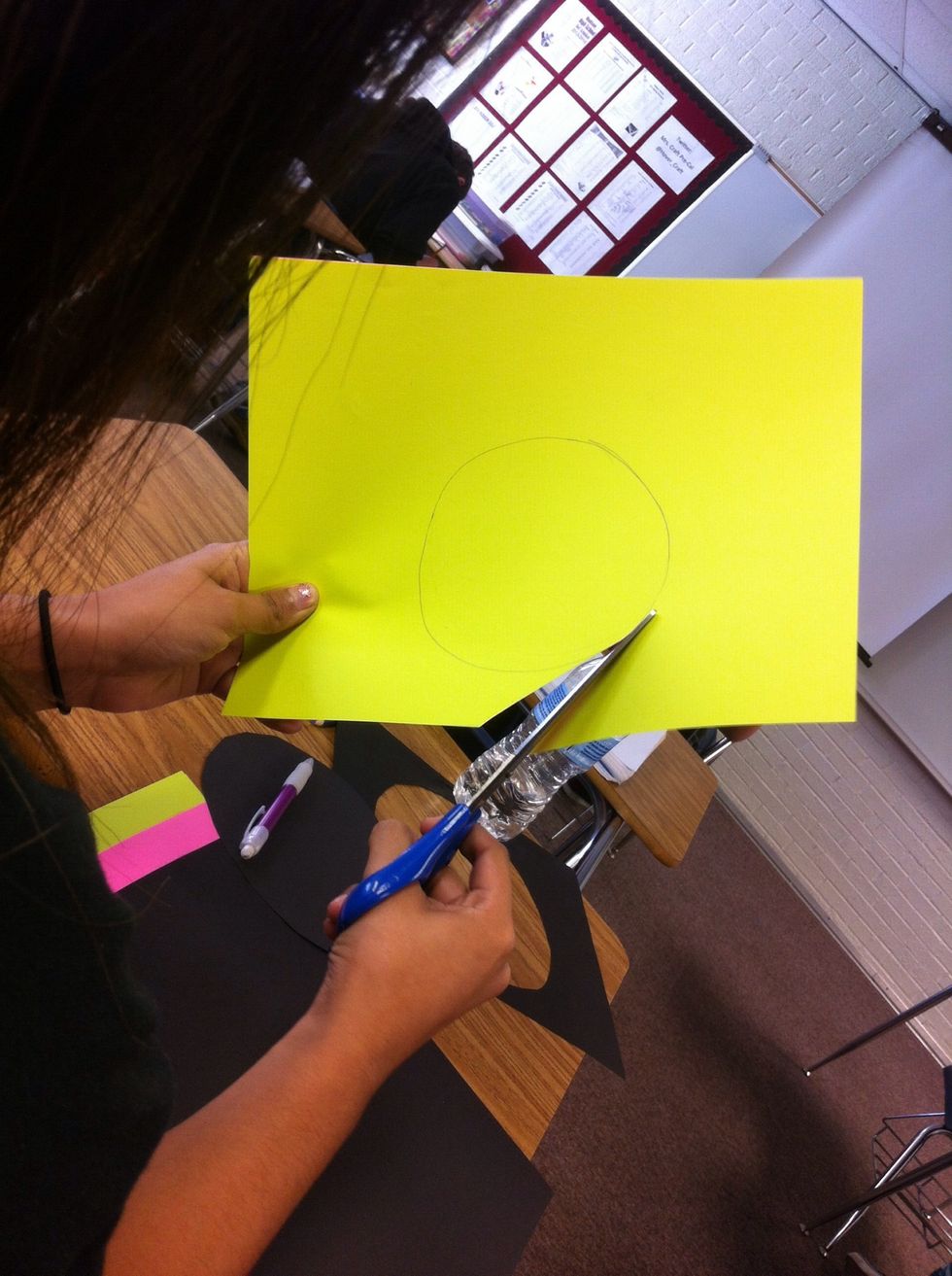 Begin cutting the circle with the green paper still overlapping the pink.