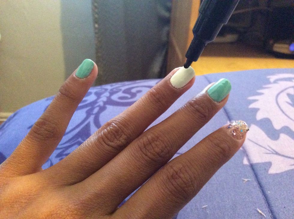 Begin drawing either chevron lines or squiggles on the white painted fingers.