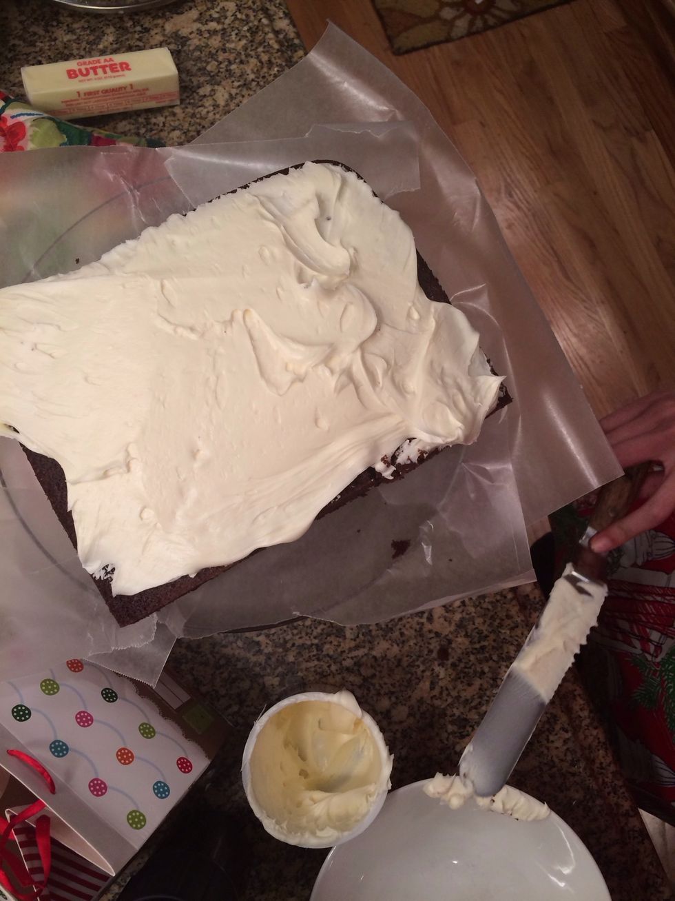 Begin frosting the top of the cake. It helps to put a large dollop and spread around so that the cake doesn't "smear."