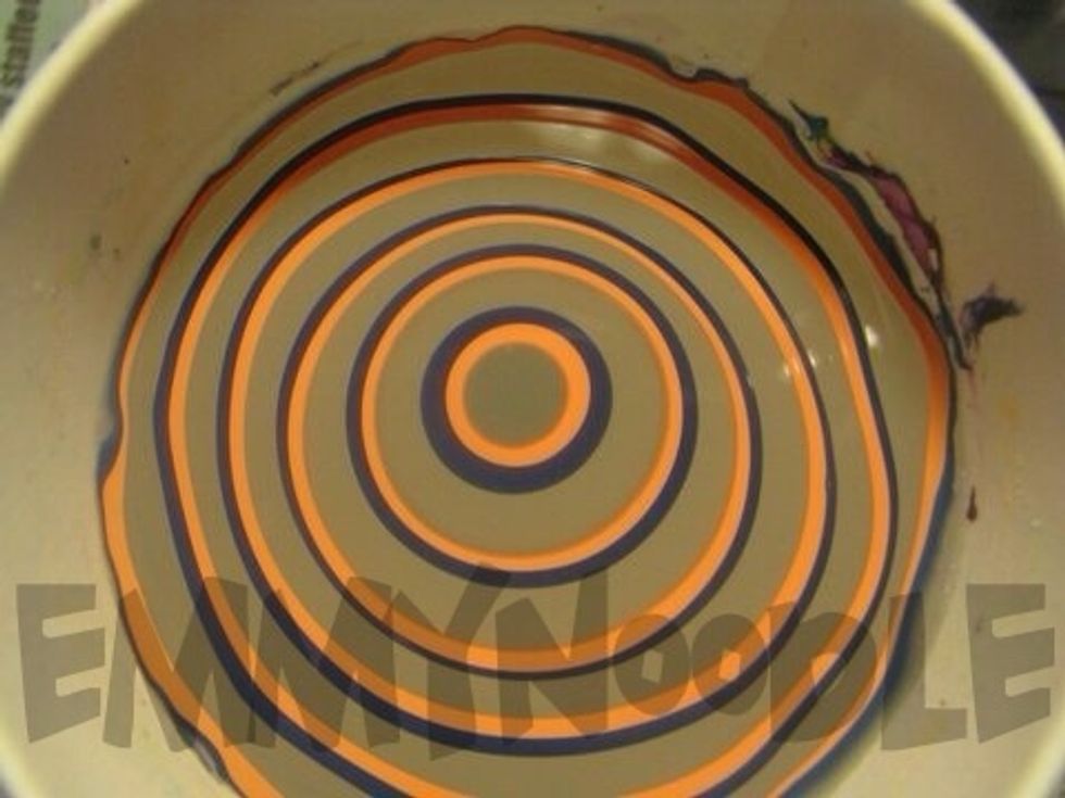 Begin making a bullseye of your three colors in the water by dropping a single drop of polish into the water and allowing each to expand. Repeat around 4-5 times with each color as shown above.