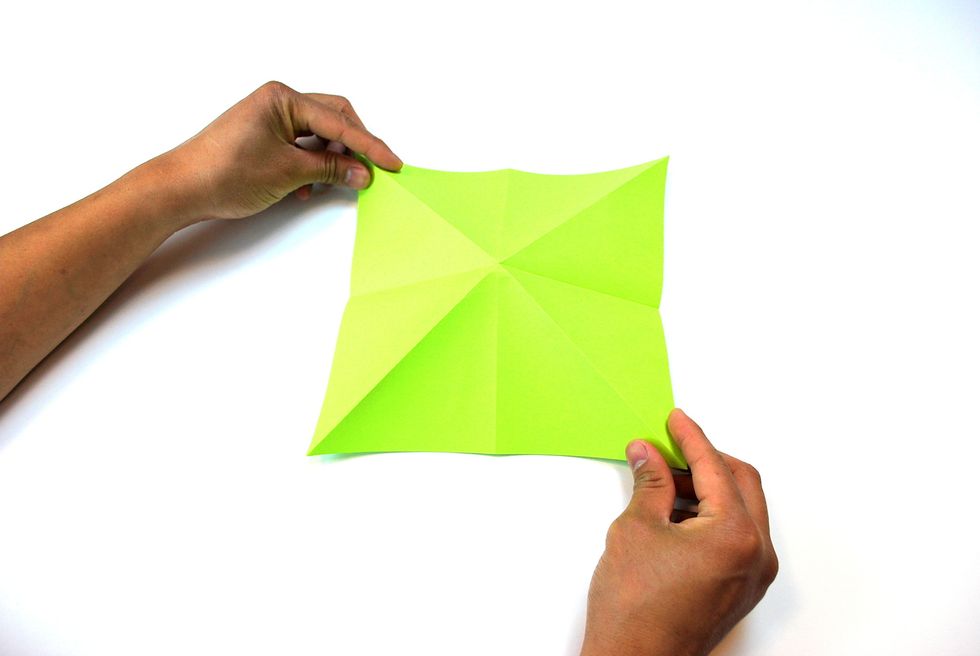 Begin to fold the paper into a pyramid-shape by pushing the corners in and bringing the center of the paper up, as shown in the picture above.