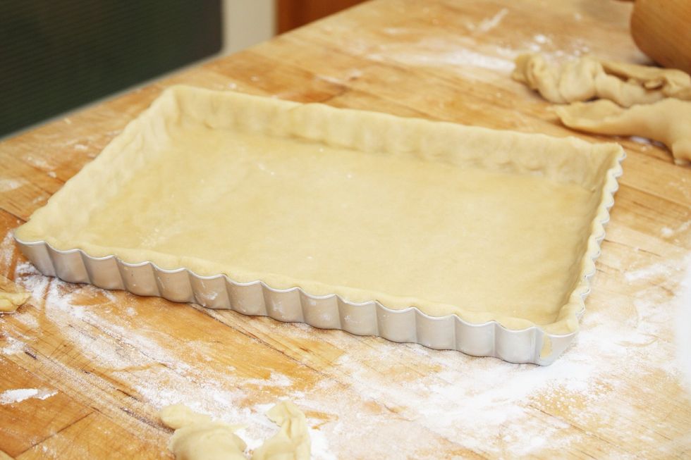 Begin with lining your tart mold with desired crust. Use a plain pie dough or other pastry dough appropriate for savory applications.