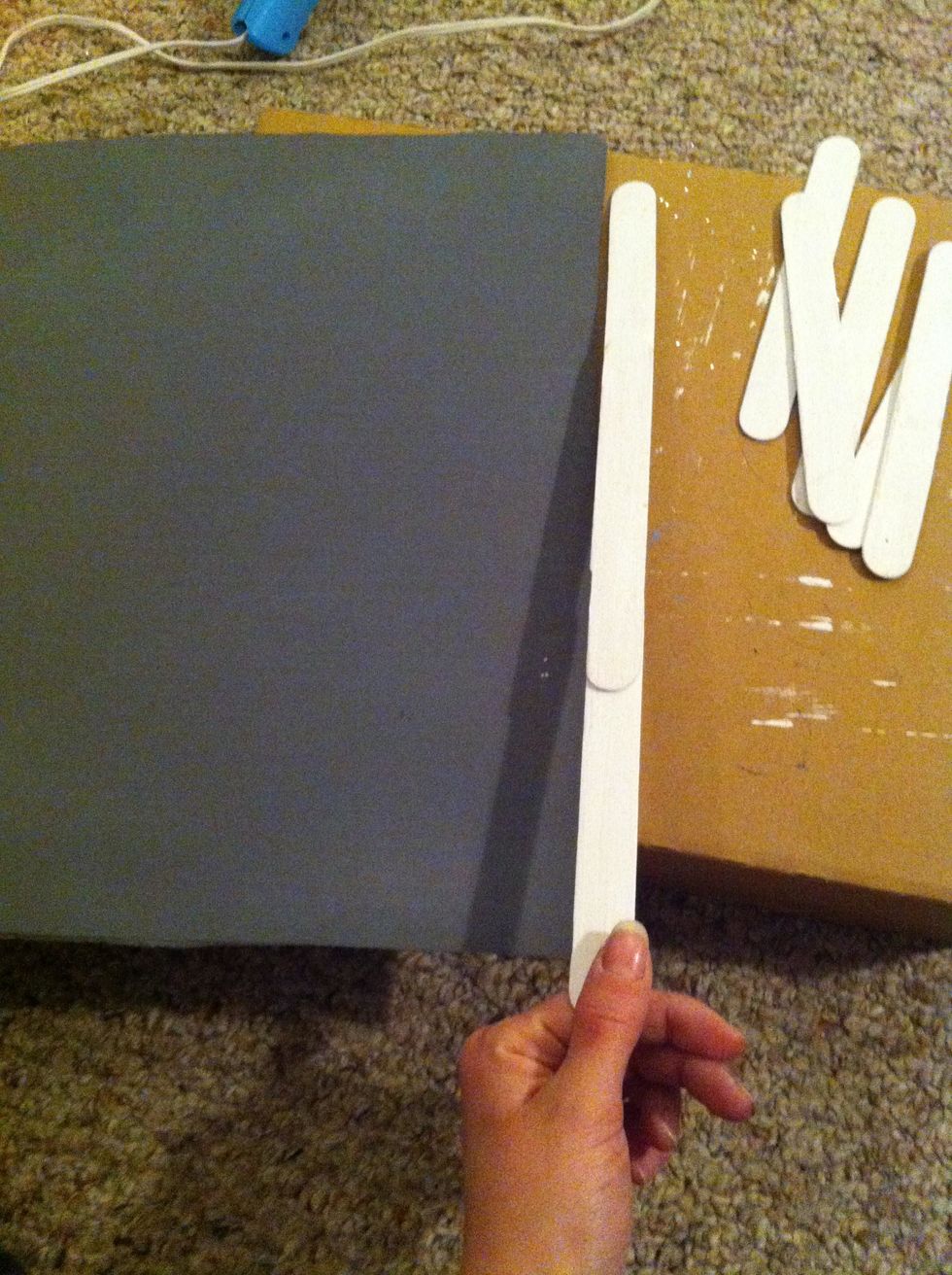 Begin your frame. Line the sticks up to be the length of each side of your card board and hot glue them together.