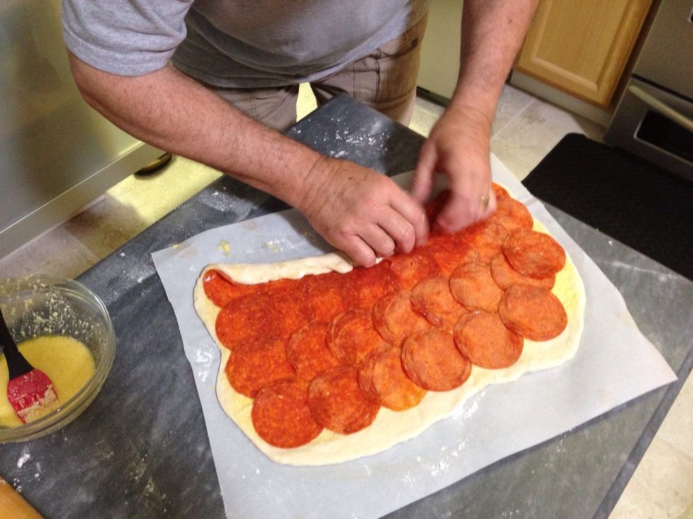 Beginning with the long side where you started with the pepperoni, start rolling the dough up - make this first turn pretty tight so you can roll the rest of it easily.