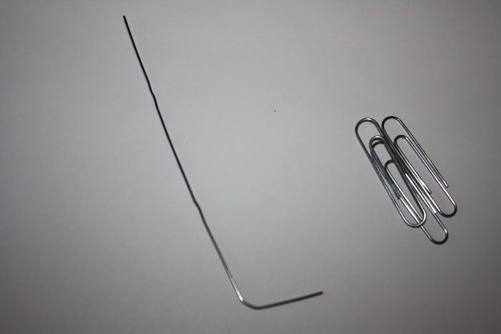 Bend a paper clip like this, and put the bent end into the hole where the motor would go