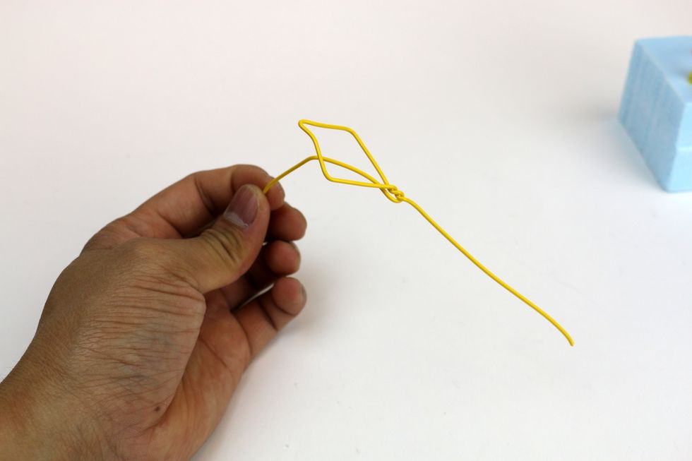Bend one end forward to make it looks like a rope. The other end will be shorter and trail behind the kite like a tail.