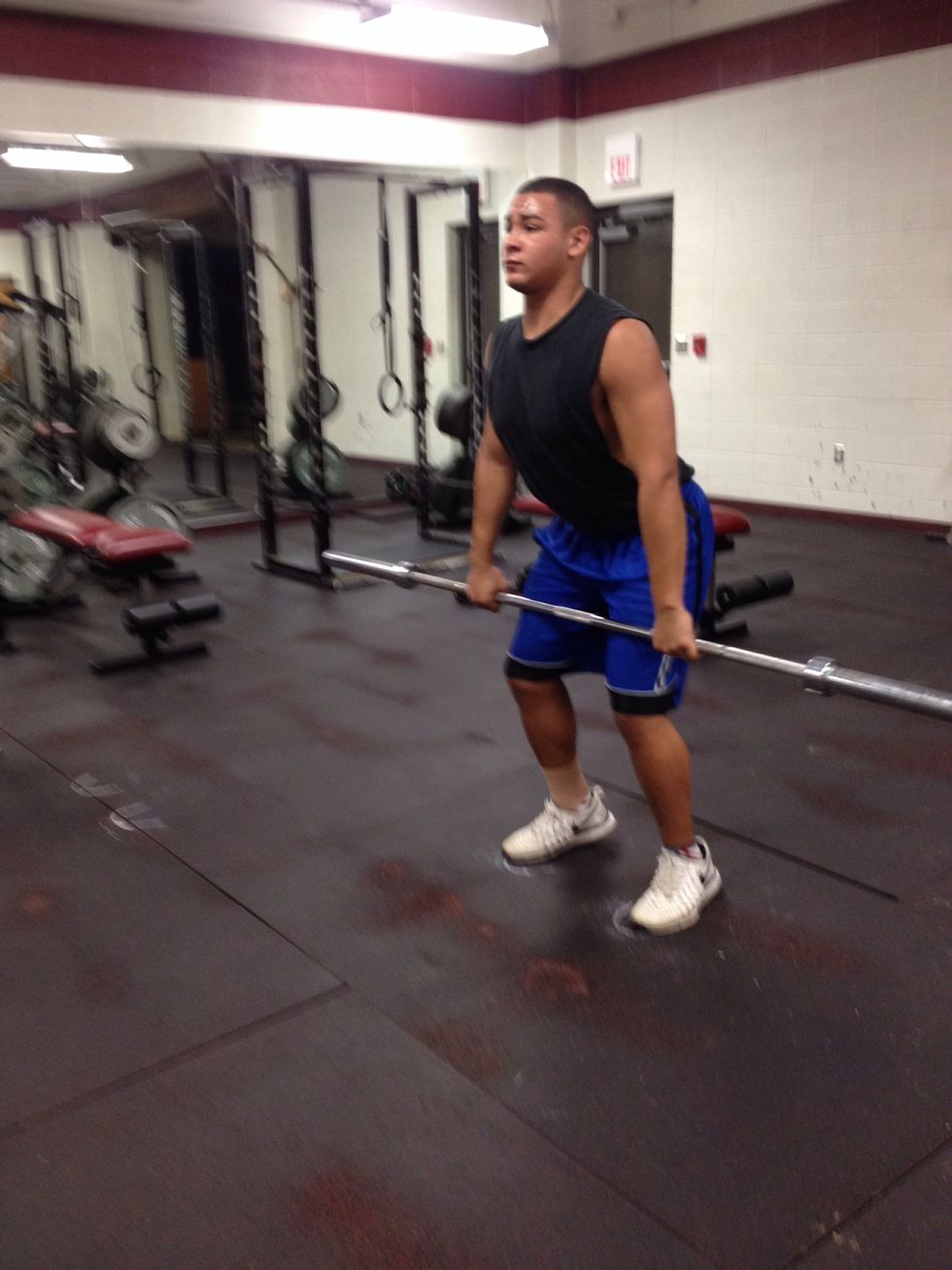Bend your knees slightly, let the bar hang above your knees.