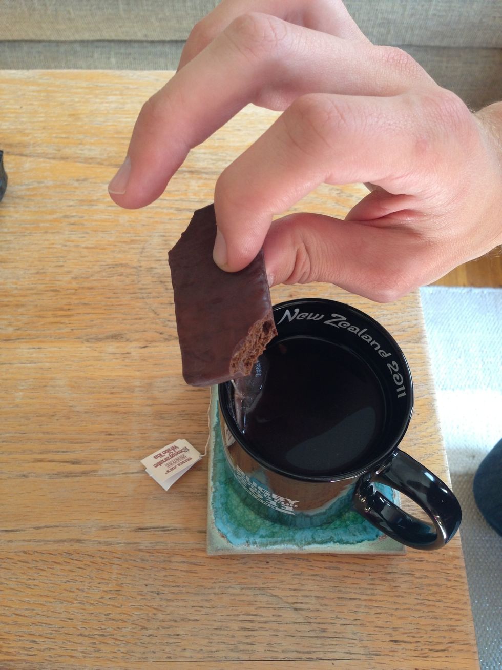 Bite off opposing corners of the Tim Tam.