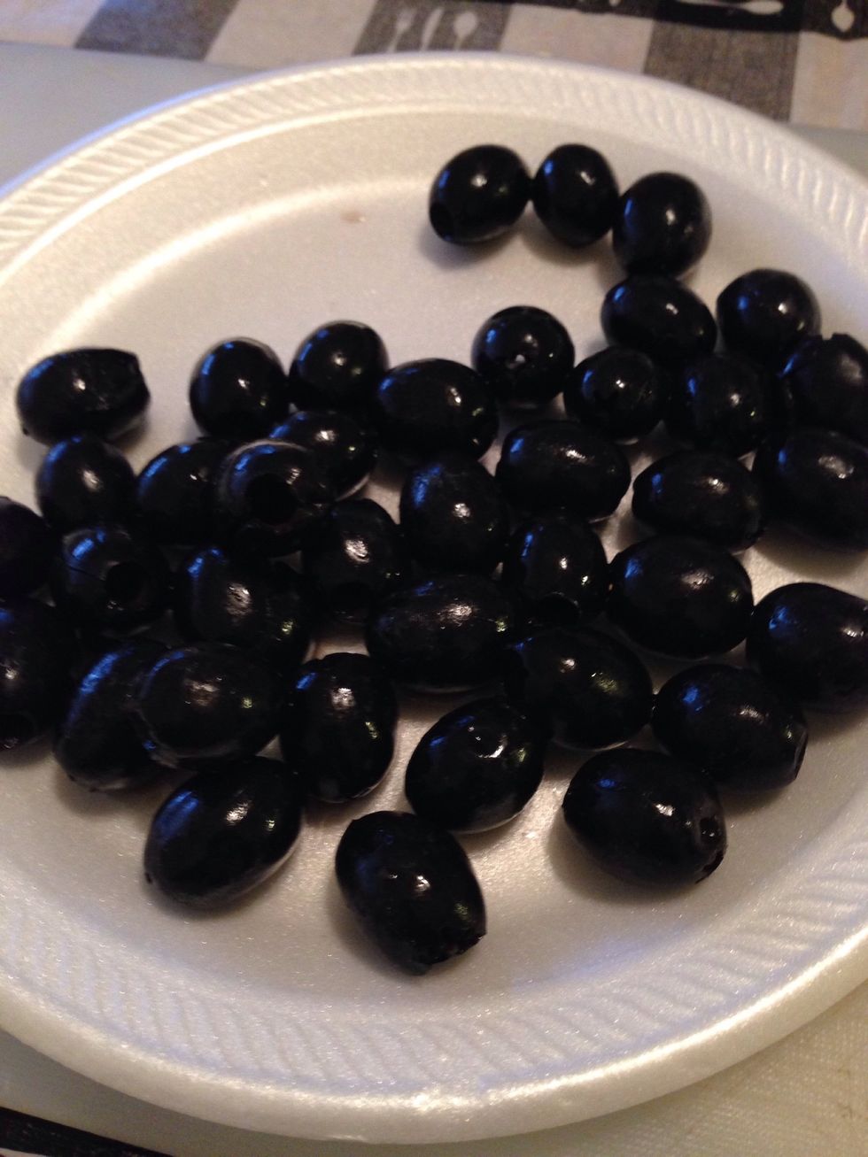 Black olives time, if your using a can of olives, make sure to carefully open the can with a can opener and drain the olive juice out. Place on a plate and get ready to chop them.