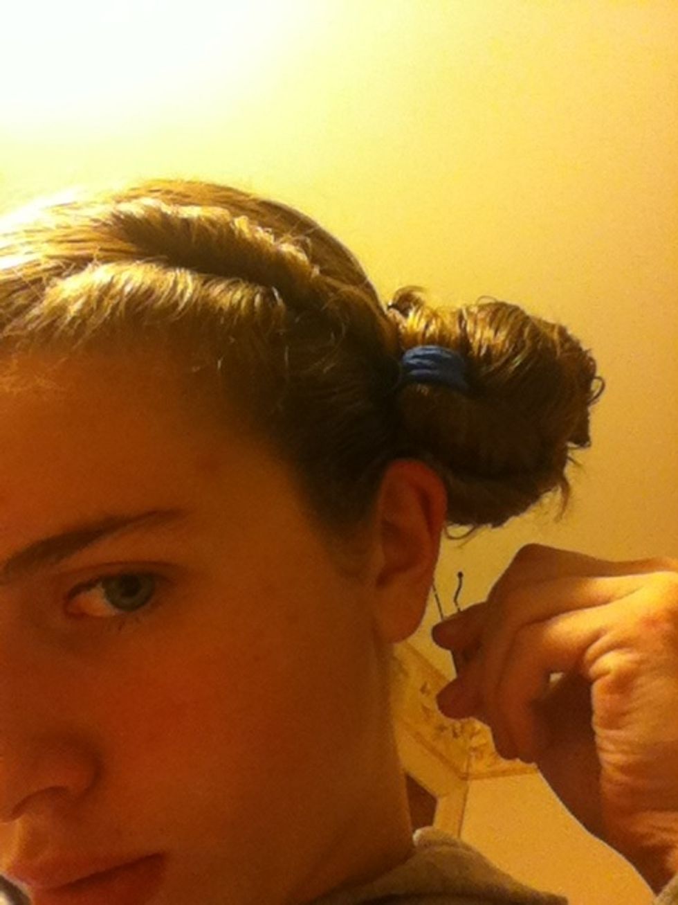 Bobby pin the bun to the hair on the scalp.
