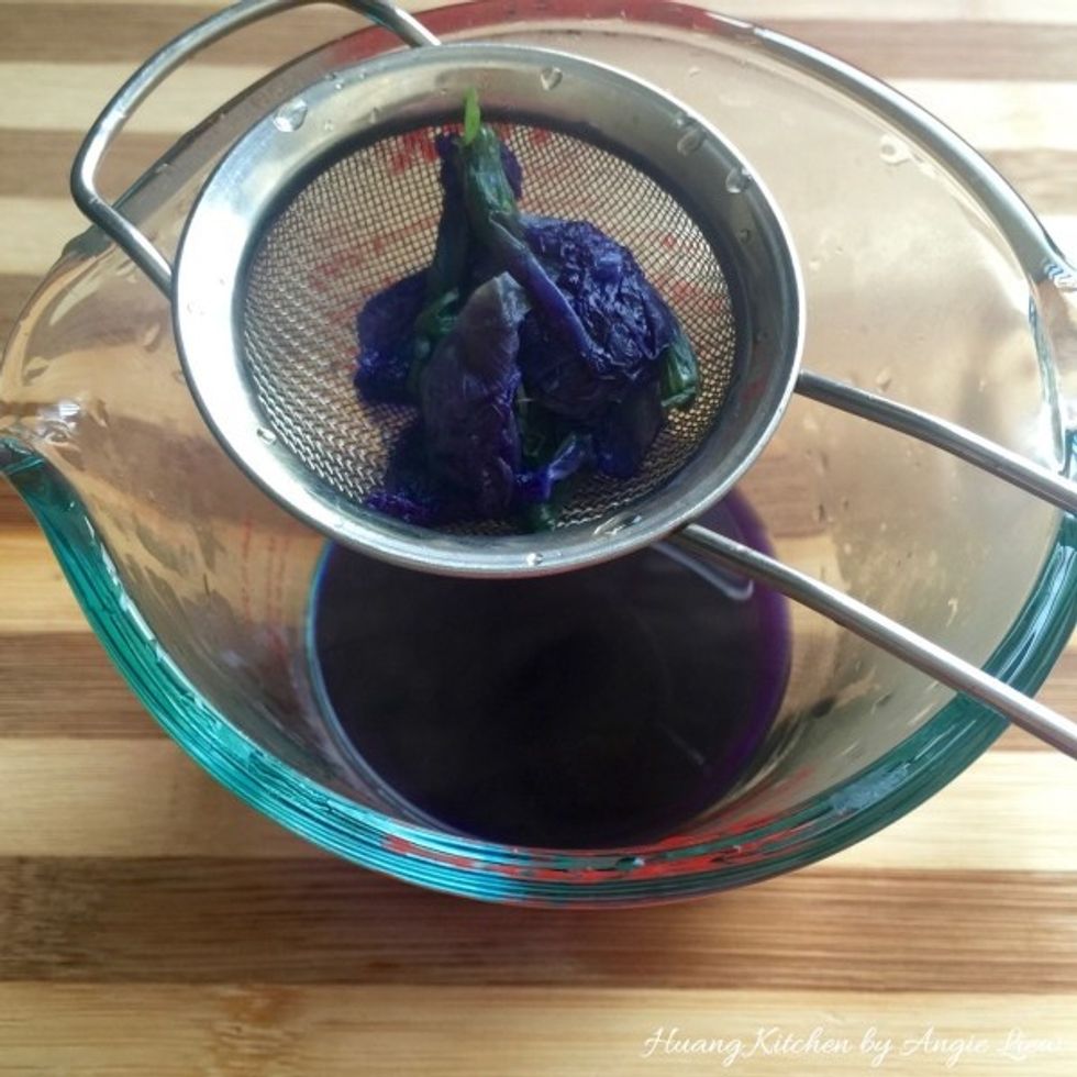 Boil the blue pea flowers in a pot slowly to extract the blue colour. Then strain the blue colour extract for use as colouring for the dough.