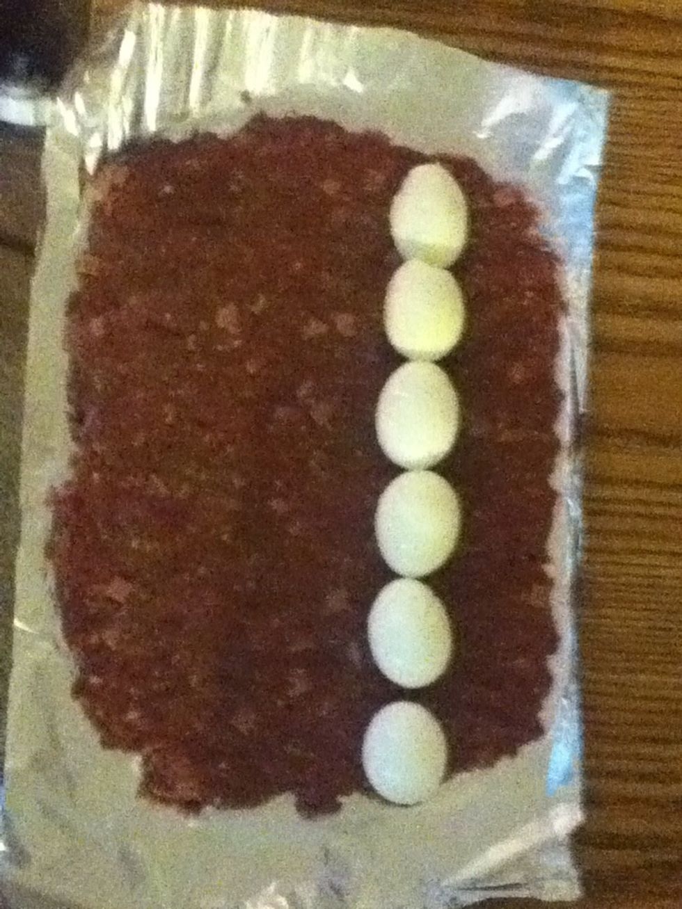 Boil the eggs until they are nice and hard. Peel them and put them on one side of the ground beef