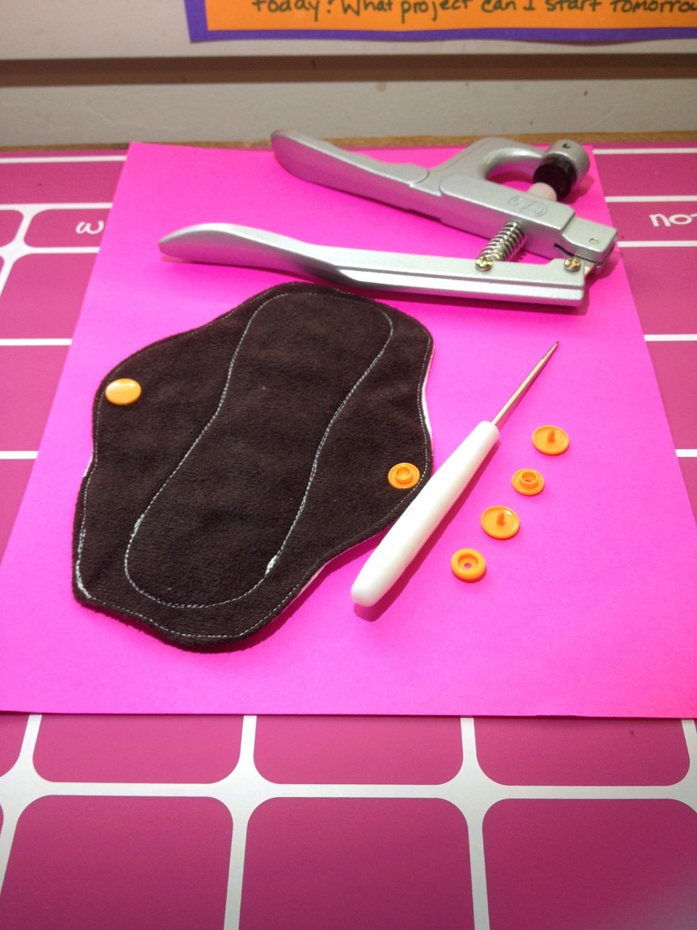 Bottom side of pad with orange snaps added to wings. Included snap parts needed, awl and pliers. The die is T5, which is a 20 size snap (maybe 16?). Buttons, metal snaps and velcro are all options.