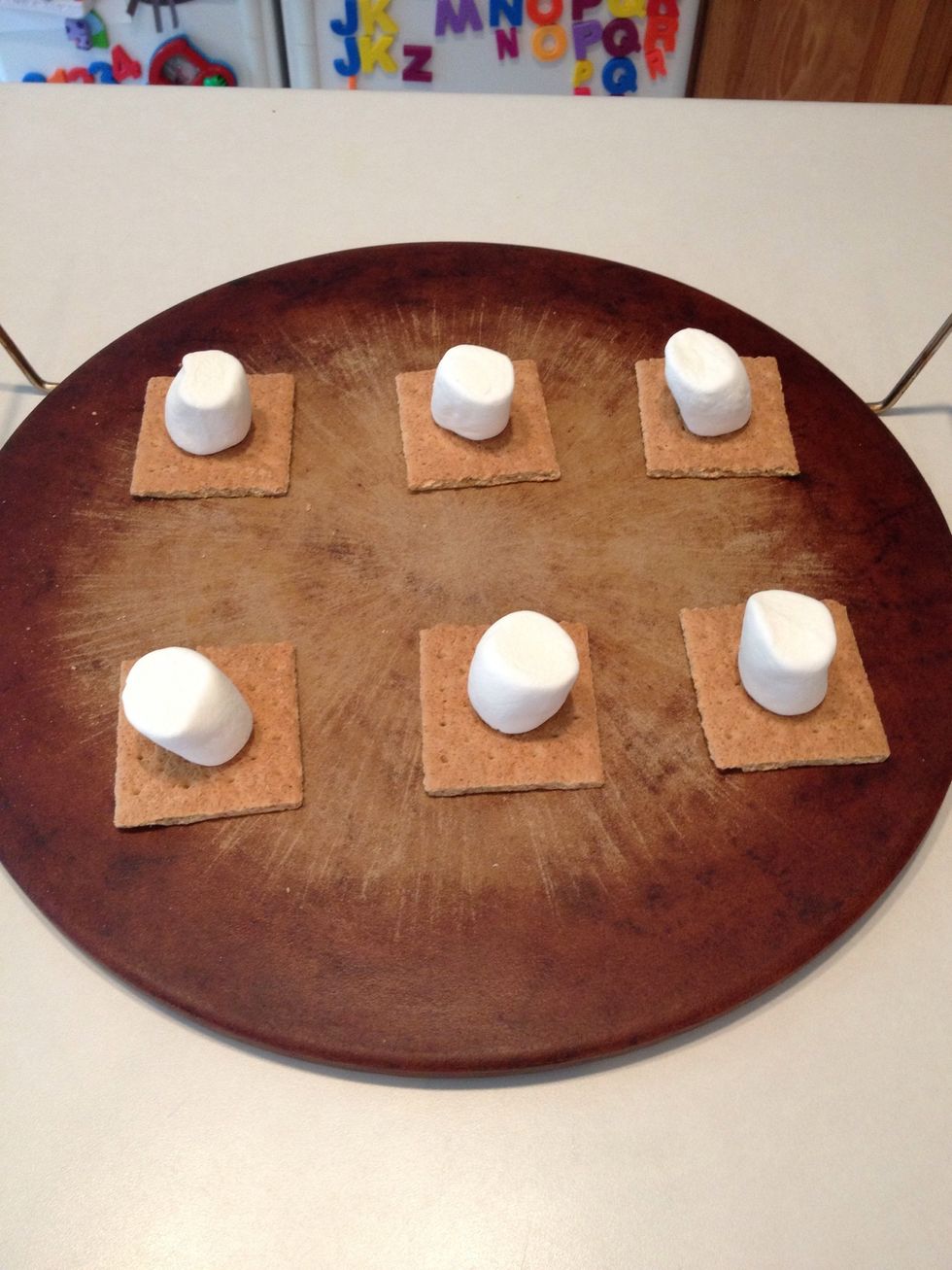 Break graham crackers into squares and place on a baking pan. Place one large marshmallow on top of each graham cracker.