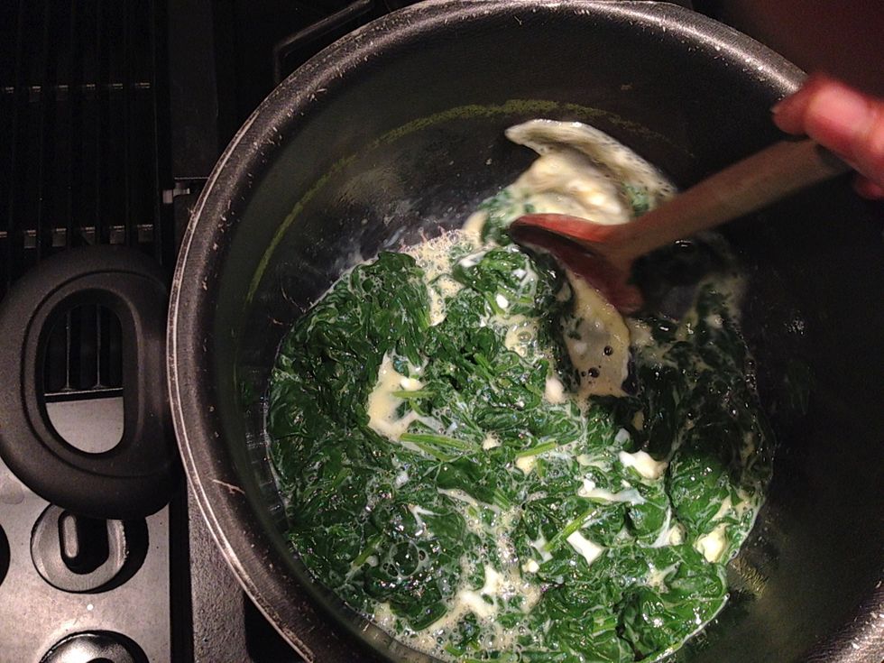 Break the eggs and start stirring to help cook the eggs and mix the eggs and the milk throughout the spinach.