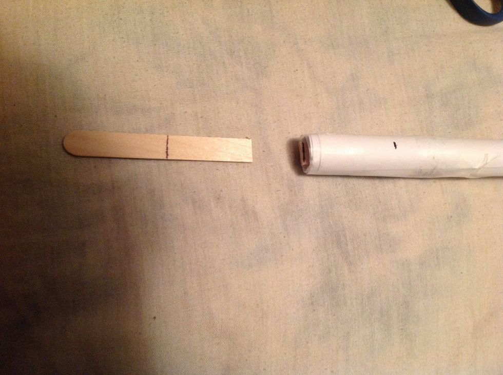 Break the end of the popsicle stick off inside the tube at that mark that you made.