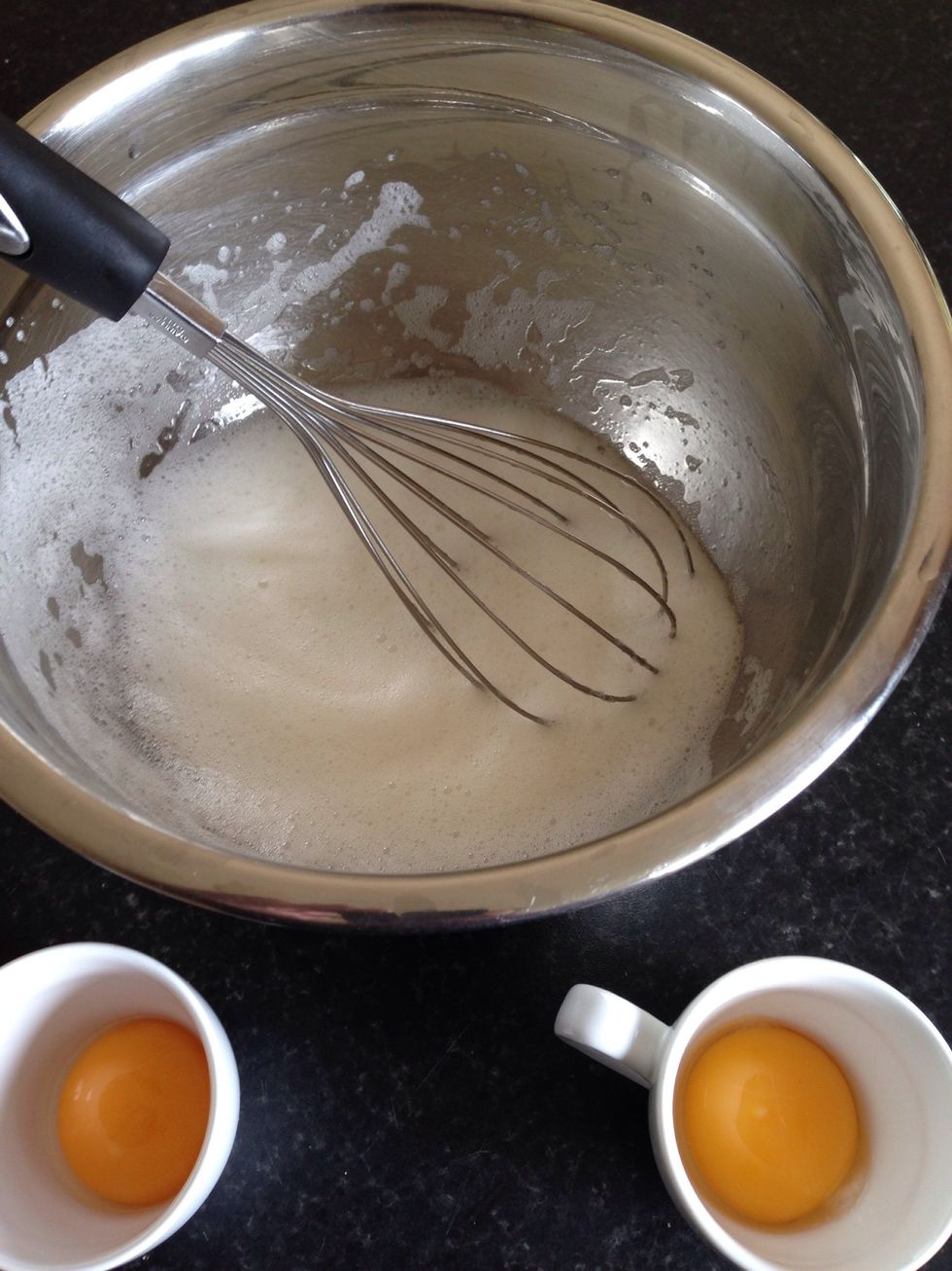 Break two eggs and put the whites into a big bowl and the yolks into small cups. Add a pinch of salt to the whites and whip until stiff.