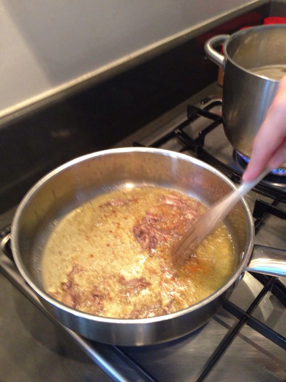 Break up the anchovies and add garlic and crushed pepper