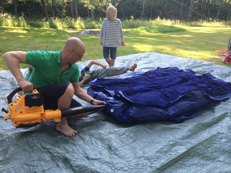 Bred ut presenningen p\u00e5 marken och l\u00e4gg Restaformen (uppbl\u00e5sbar extras\u00e4ng) ovanp\u00e5. Anv\u00e4nd den bensindrivna l\u00f6vbl\u00e5sen f\u00f6r att snabbt bl\u00e5sa upp Restaformen.