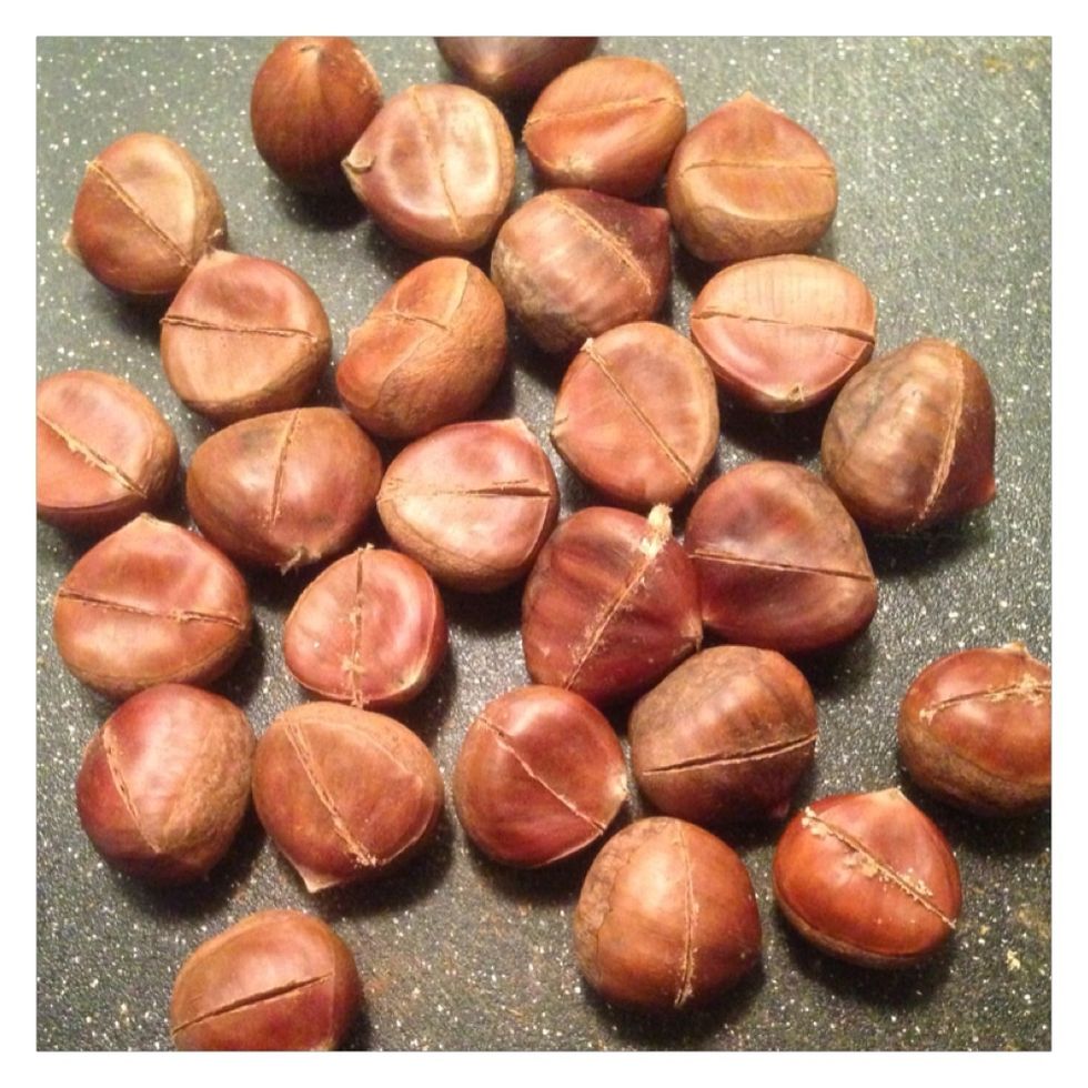 Bring a medium sized pot of water to a boil. While the water heats, cut a slit into each of the chestnuts. Cut slits through to the chestnuts.