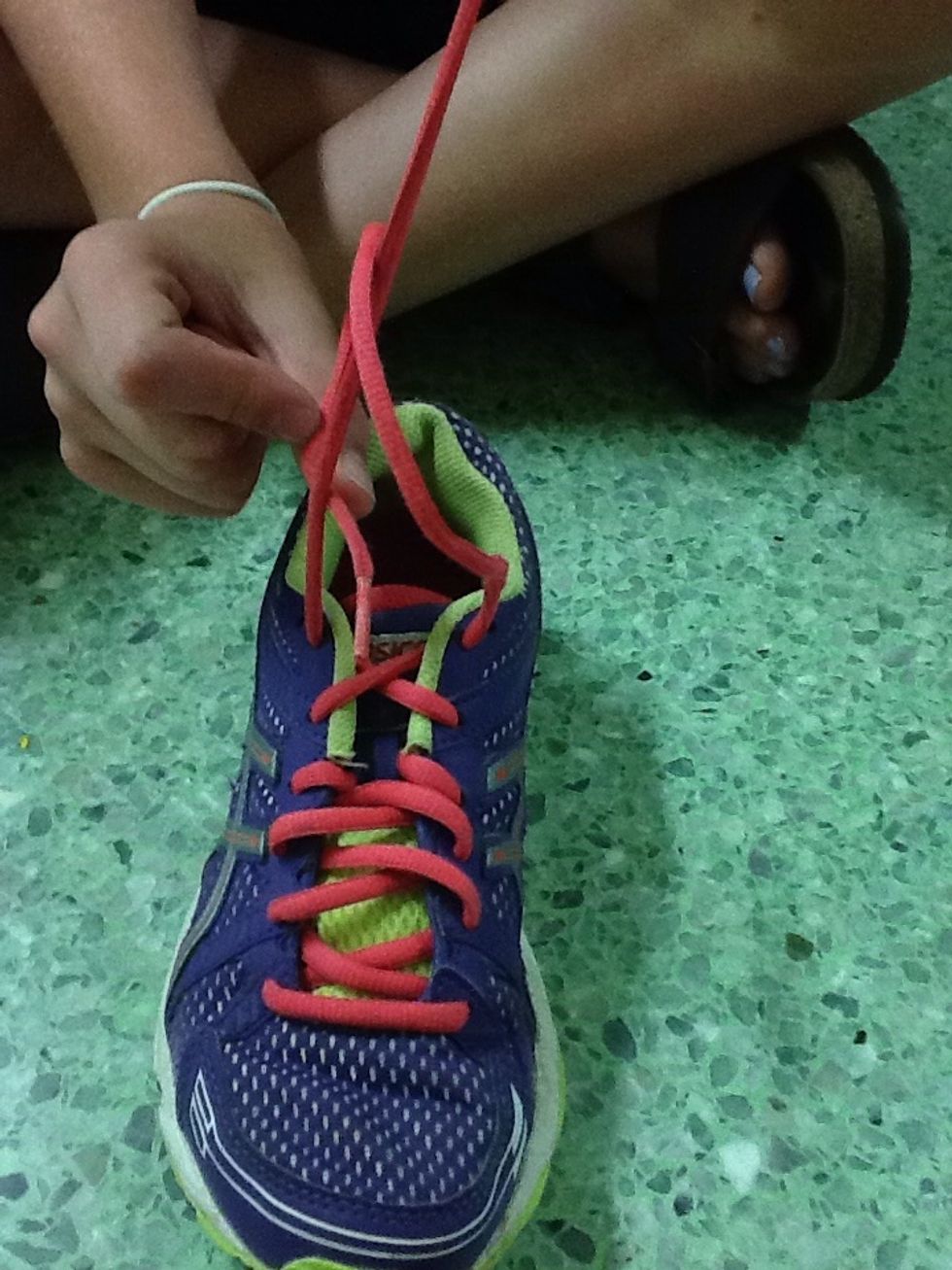 Bring one of the laces through the bottom of the X