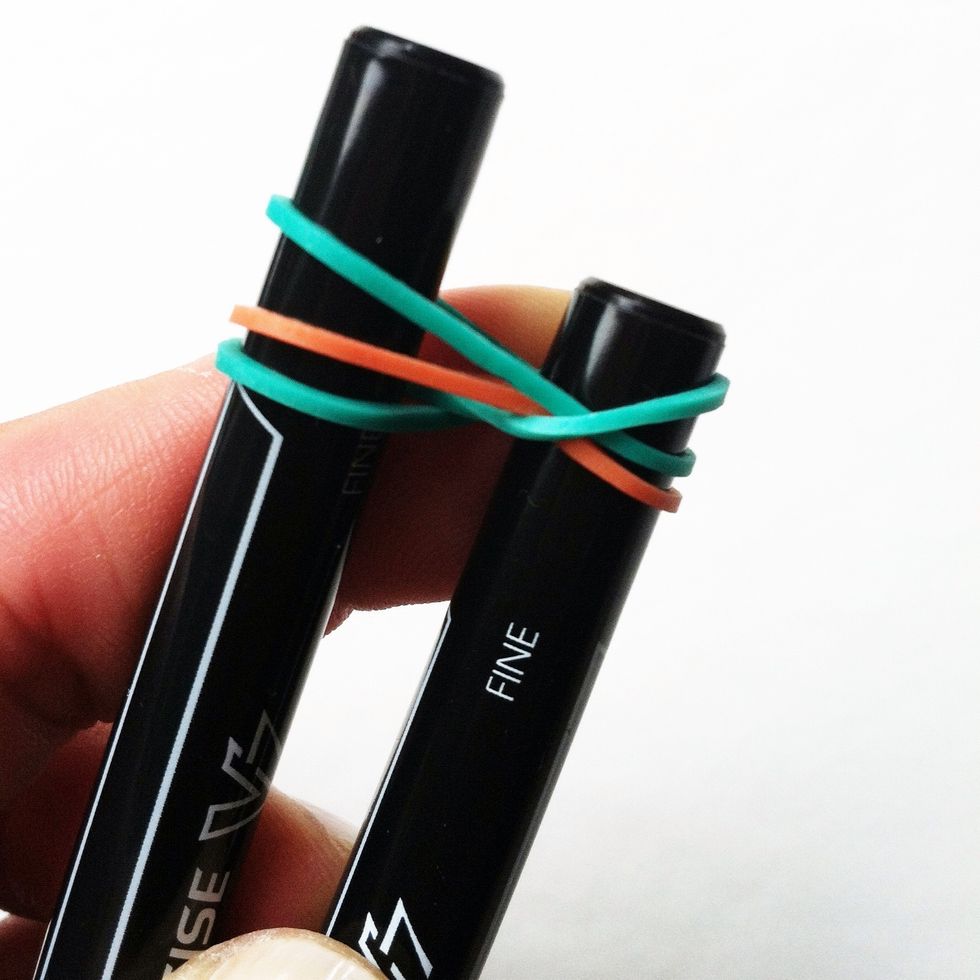 Bring the bottom right elastic over the top of the pen on the right.