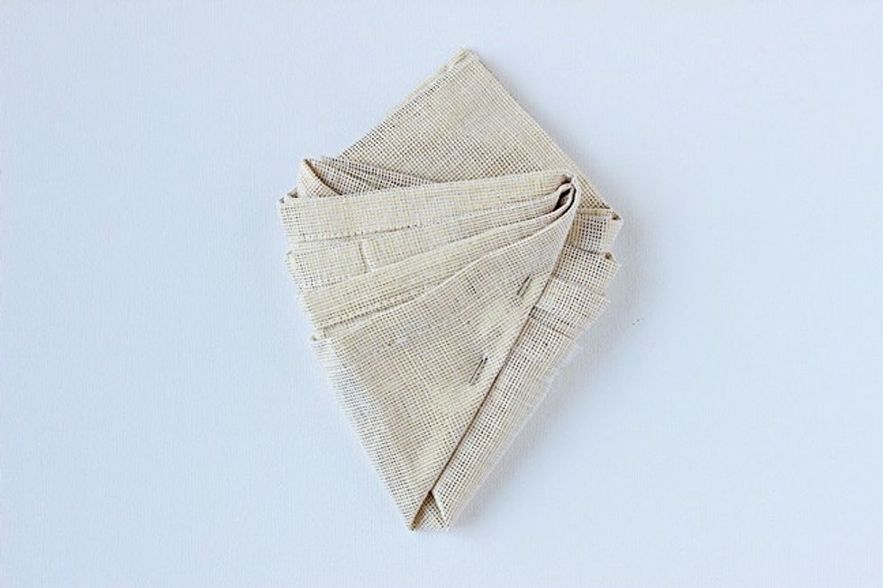 Bring the left corner up and to the right side, going on top of the area you folded in step three. To make sure everything stays put, I used a big pin to secure the two folds.