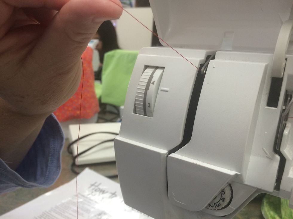 Bring the thread up and over the take up lever and then guide it back down on the LEFT side of the opening