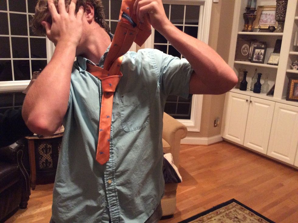 Bring the tie up into the neck loop at the top