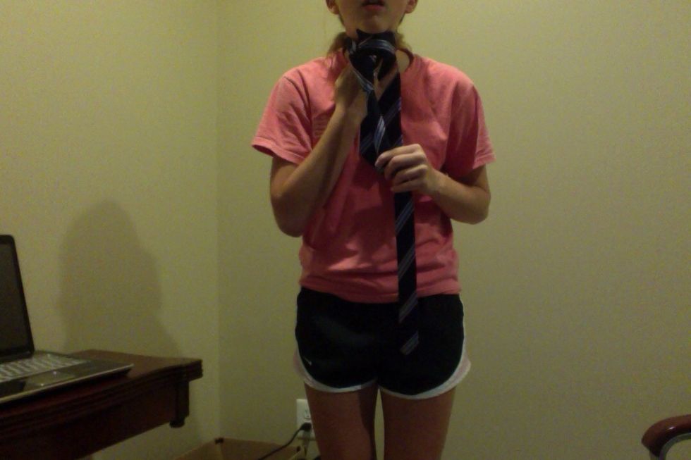 Bring the wide end up through the loop created around your neck.