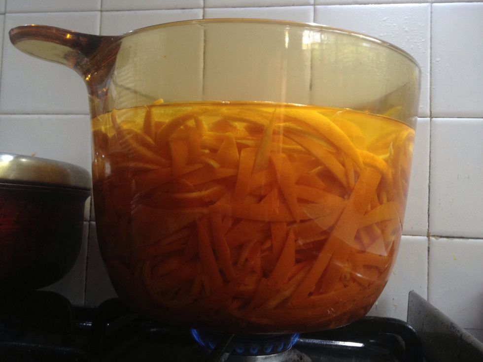 Bring water in a pot to a boil, lower heat, add orange peels and simmer for 45 minutes. Then drain orange peels, set aside and throw away water. This can be repeated if peels still tastes bitter.