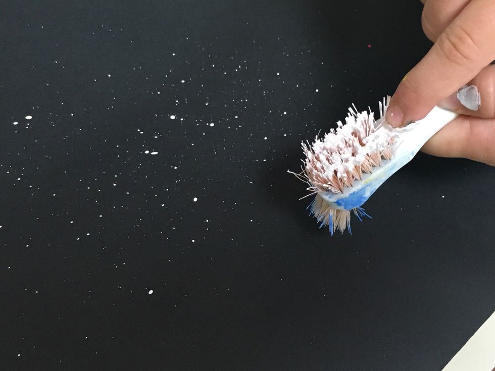 Bristles up, finger pulling back, splats splatting forward onto the paper.