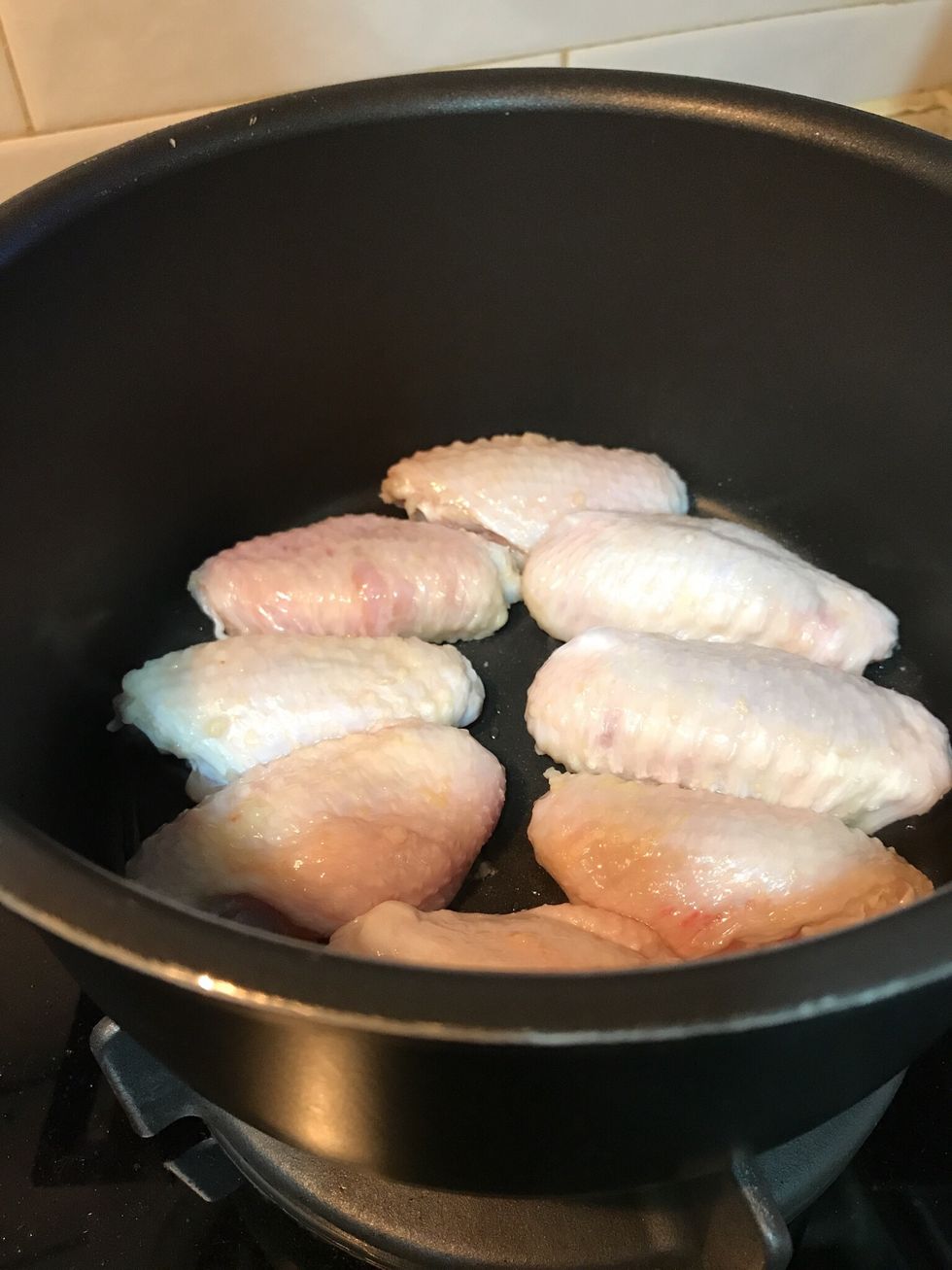 Brown chicken wings in a heated saucepan