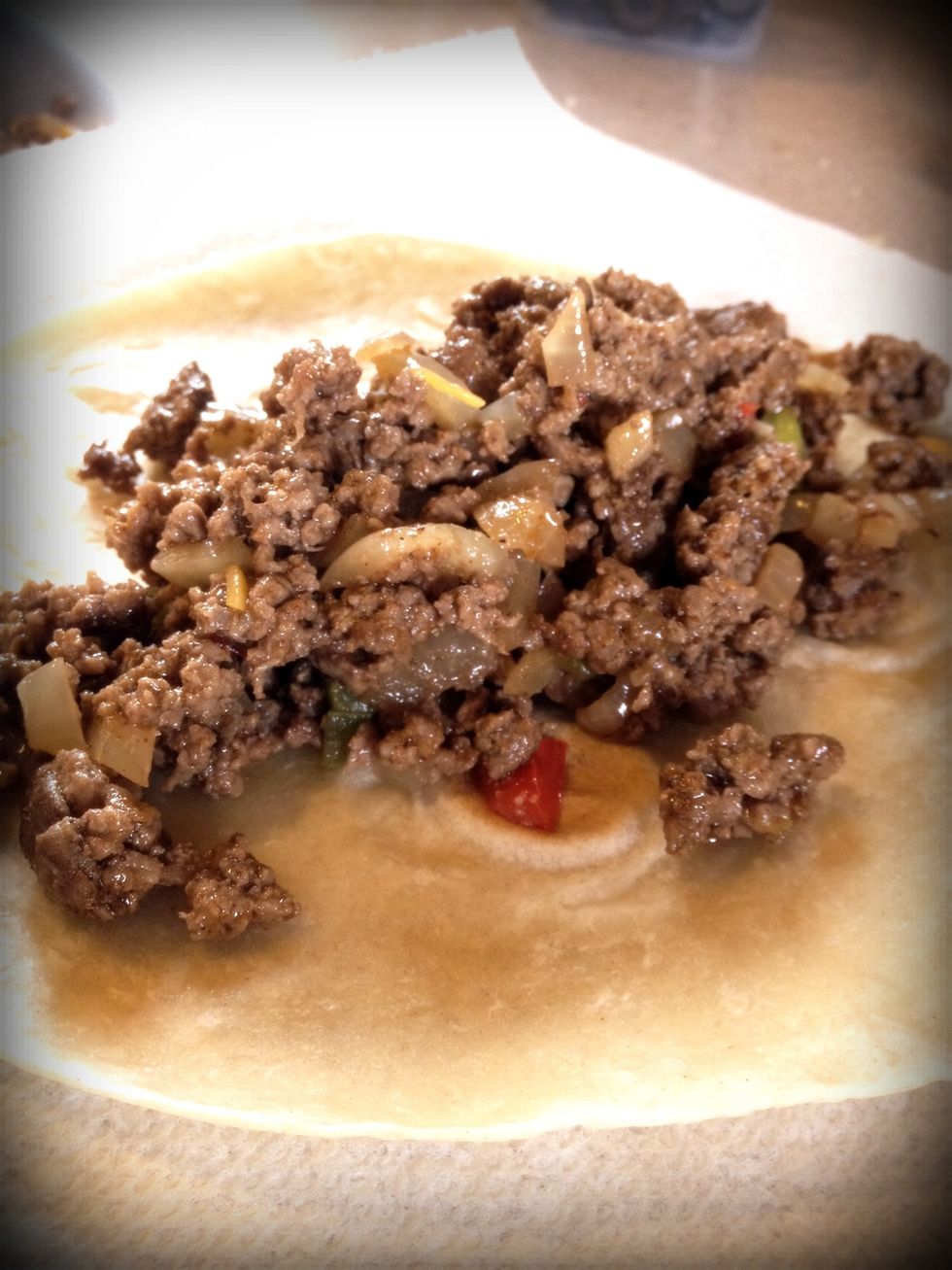Brown the beef. Add onions and peppers and cook until soft. Splash in some of the sauce. Add 1/8 of the mixture to the tortilla.