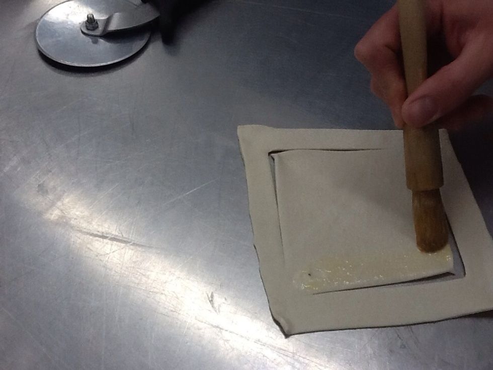 Brush egg wash around the edge of the smaller inner square.