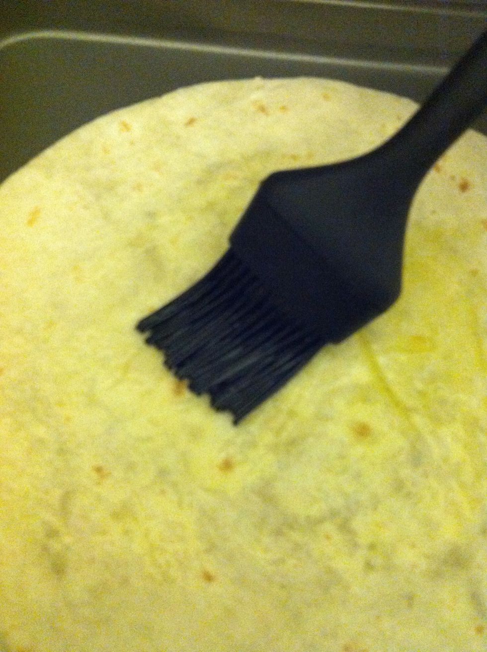 Brush on a little bit of olive oil. Just enough to cover tortilla.  Flip and put oil side down on un-greased baking sheet